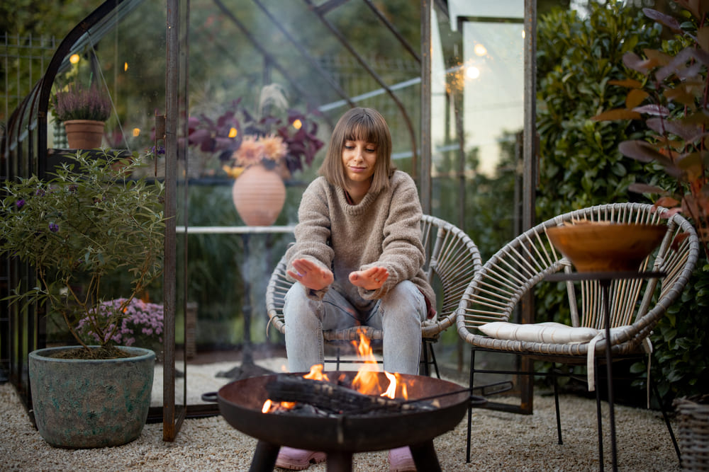 vrouw geniet van haar vuurkorf in haar tuin