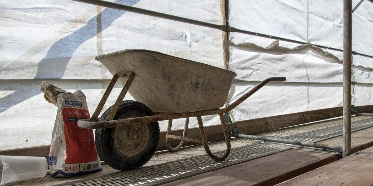 Kruiwagen op bouwplaats Krikke bouwplaats met een kruiwagen en een zak cement, passend bij een eerste verbouwing.