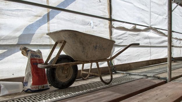 Kruiwagen op bouwplaats Krikke bouwplaats met een kruiwagen en een zak cement, passend bij een eerste verbouwing.