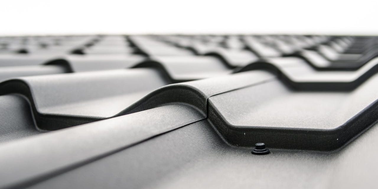 Detailopname van een metalen dakbedekking tijdens dakinspectie, met zichtbaar bevestigingspunt op het oppervlak