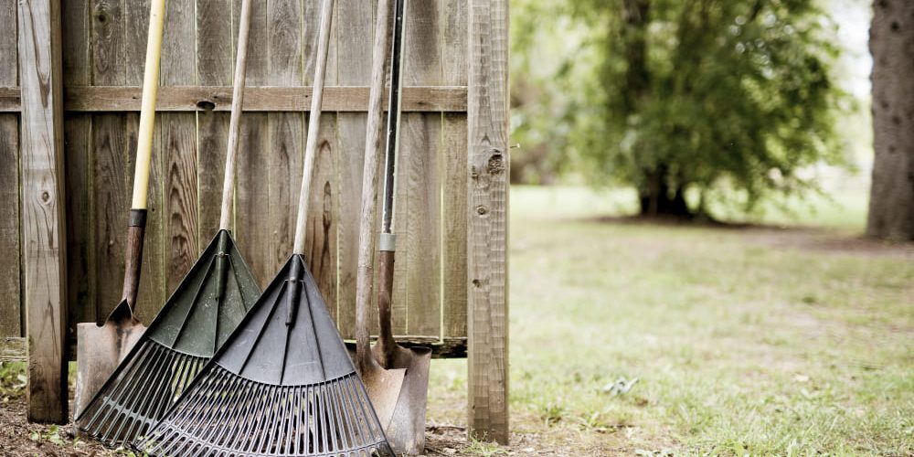 meerderen harken en scheppen tegen een schutting aan