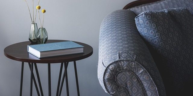 Een bank met daar naast een tafeltje waar een boek op ligt en een twee plantjes op staan