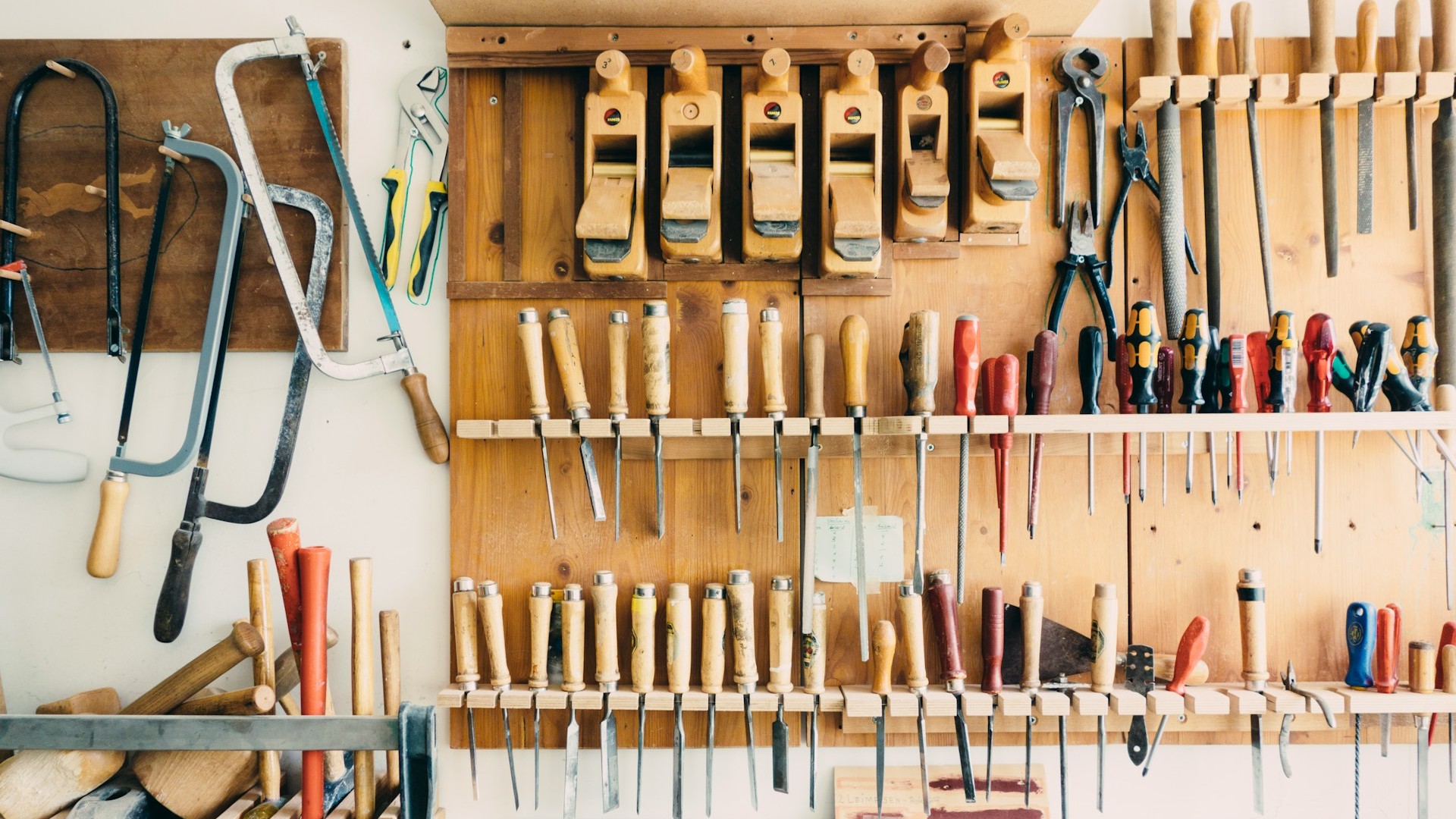 Garage indelen met overzichtelijk opgehangen handgereedschap aan houten wandrek
