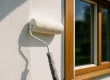 Verfroller brengt witte verf aan op voorbereide huismuur buitenschilderwerk