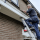 man op een ladder schildert een dakrand