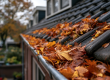 : Dakgoot van een huis gevuld met opgehoopte oranje herfstbladeren.